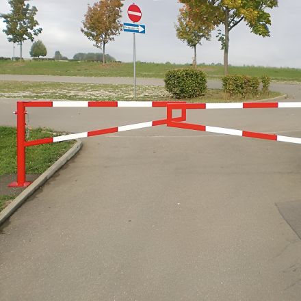 Red & white swing gate barriers across the entrance of a road.